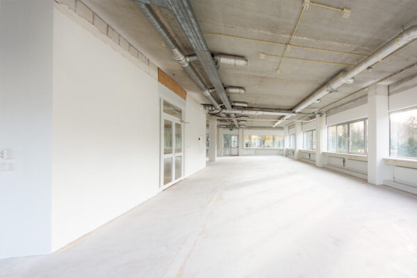 Lichte, lege kantoorruimte aan de Huis-ter-Heideweg met betonnen plafond en grote ramen.